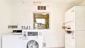 A laundry room with a front-loading washer, a stacked dryer, and a small window. - Go 2 By Relianse - Pittsburgh, PA - Cafton (Pittsburgh)
