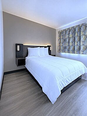 A modern hotel room with a large bed, a nightstand, and a patterned wall. - Go 2 By Relianse - Pittsburgh, PA - Cafton (Pittsburgh)