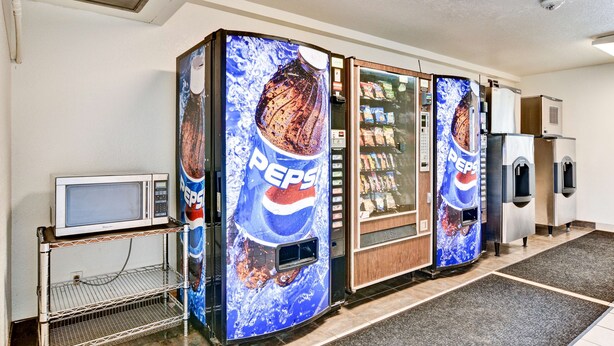 A vending area with Pepsi refrigerators and a microwave on a metal rack. - Go 2 By Relianse - Pittsburgh, PA - Cafton (Pittsburgh)