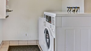 A laundry room with a front-loading washer and dryer, a wall-mounted utility cabinet, and a set of four water faucets on the wall. - Go 2 By Relianse - Pittsburgh, PA - Cafton (Pittsburgh)