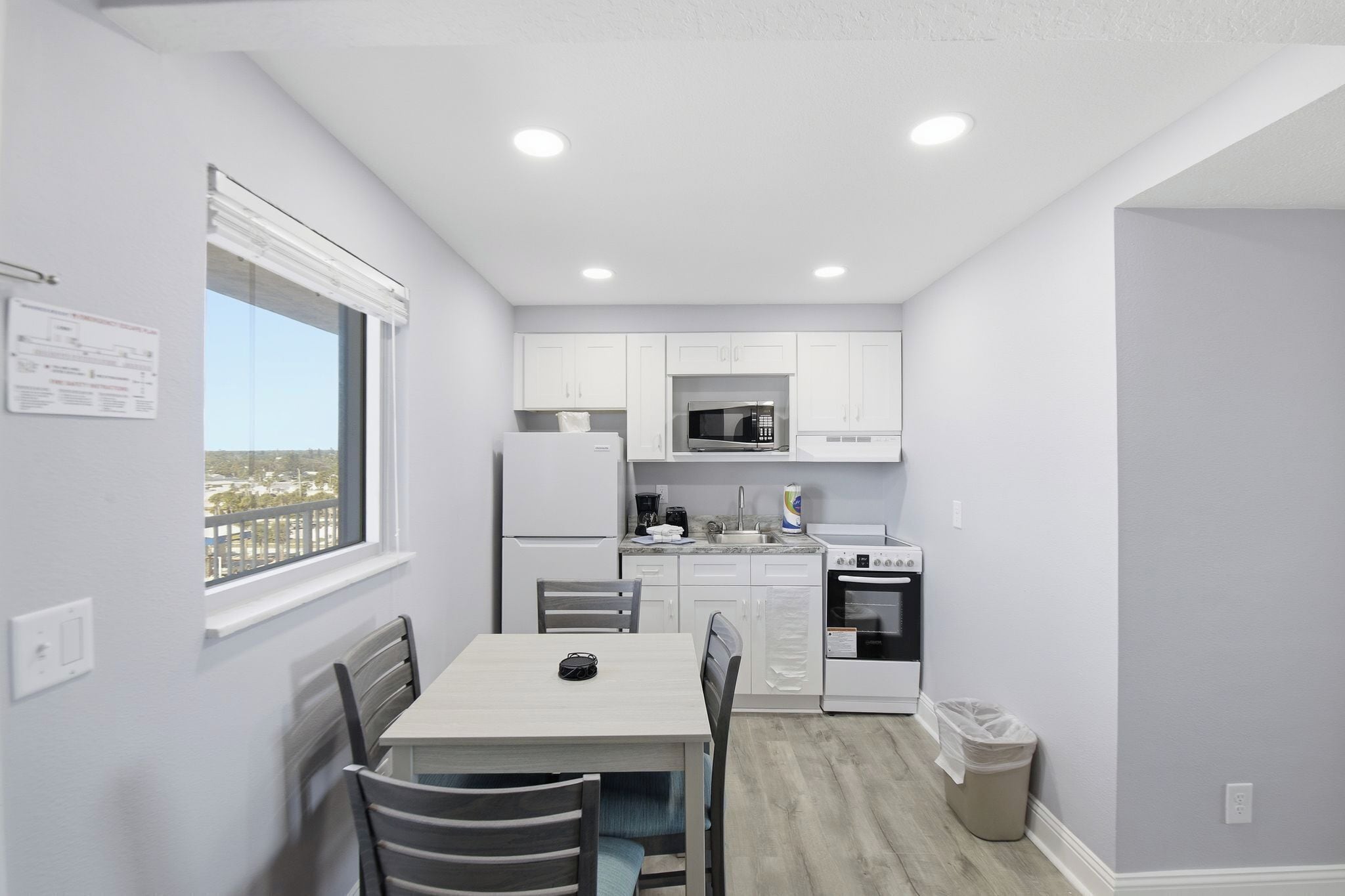 A modern kitchen with white cabinets, a microwave, stove, and a window overlooking a cityscape.