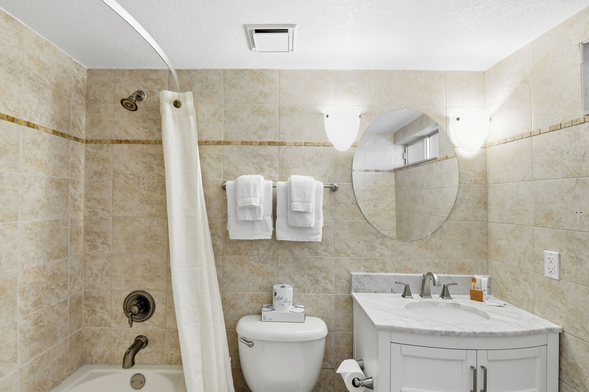 A bathroom with a bathtub, toilet, sink, and a mirror.