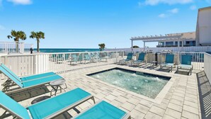 Area piscina sul tetto con lettini e vasca idromassaggio, vista sull'oceano.