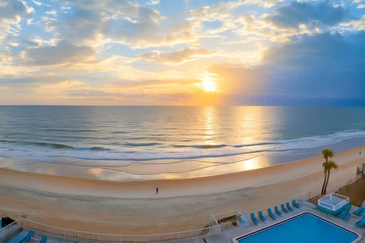 Une vue sur la plage avec une piscine et des chaises longues.
