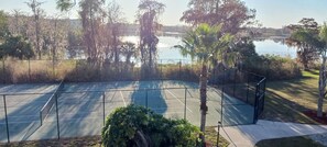 Enjoy a game of tennis surrounded by serene natural surroundings and a tranquil body of water.