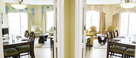 A dining area with a table set for four, two armchairs, and a sofa.