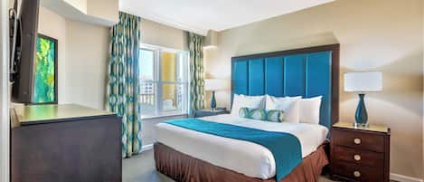 A hotel room with a large bed, a flat-screen TV, a desk, and a window with curtains.