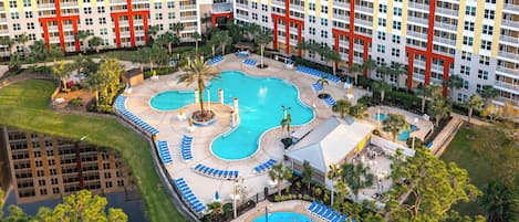 A hotel with multiple swimming pools, a landscaped garden, and a large building with balconies.