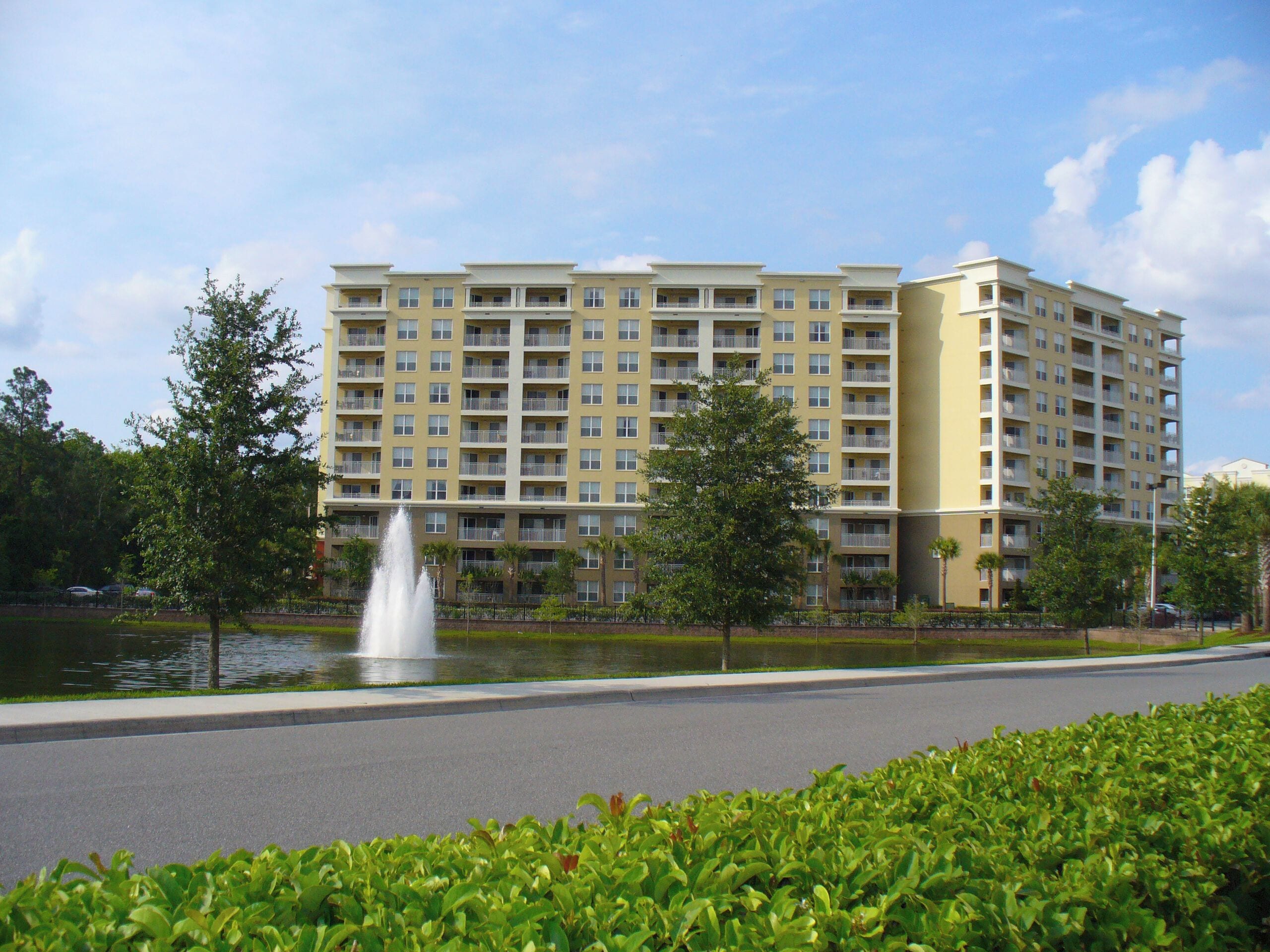 A multi-story hotel with a central courtyard, a fountain, and a well-maintained lawn.