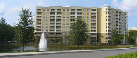 A multi-story hotel with a central courtyard, a fountain, and a well-maintained lawn.