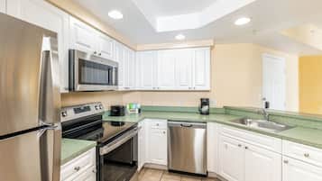 Una cocina moderna con electrodomésticos de acero inoxidable, armarios blancos y encimera verde.