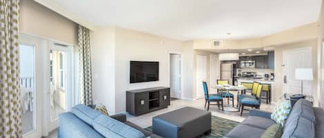 A modern living room with a sofa set, a flat-screen TV, and a dining area with chairs and a table.