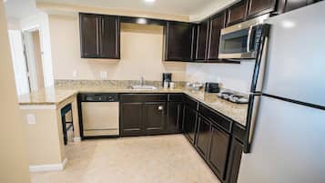 A kitchen with dark cabinets, a stainless steel refrigerator, a microwave, and a dishwasher.