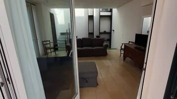 Una sala de estar moderna con un sofá, un televisor y un comedor con sillas y una mesa.