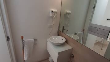 A modern bathroom with a white sink, a toilet, and a towel rack.