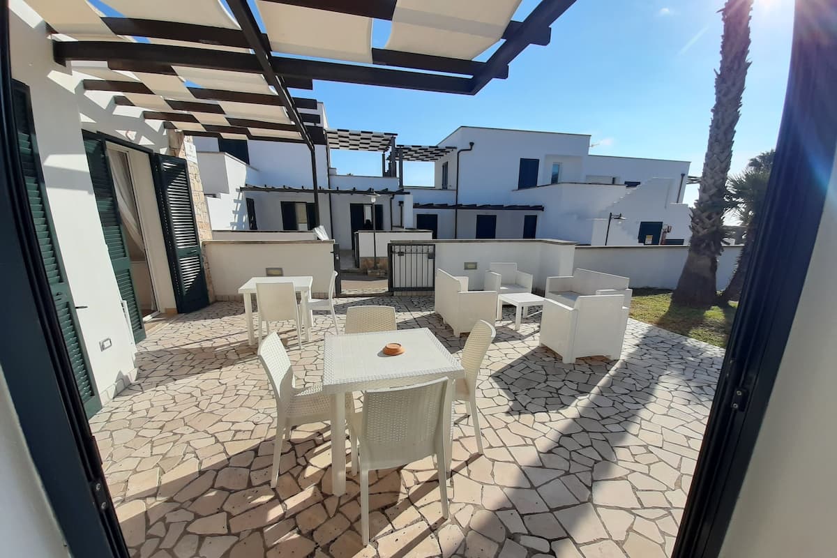 Eine Terrasse im Freien mit weißer Möbel und einem gestreiften Fliesenboden.