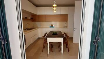 Une cuisine moderne avec une table et des chaises, un luminaire suspendu et des placards.
