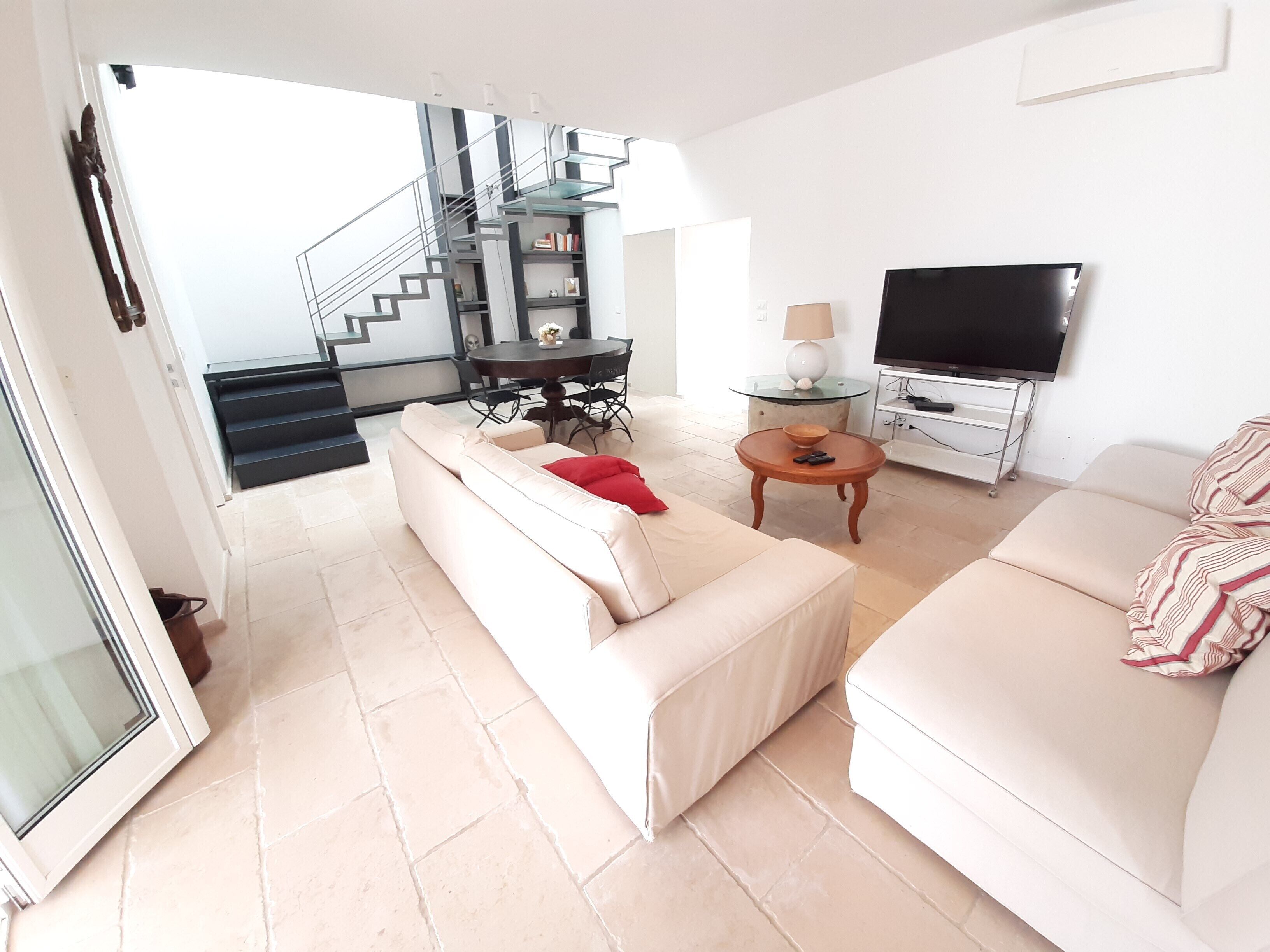 A modern living room with a staircase, a dining area, and a TV.