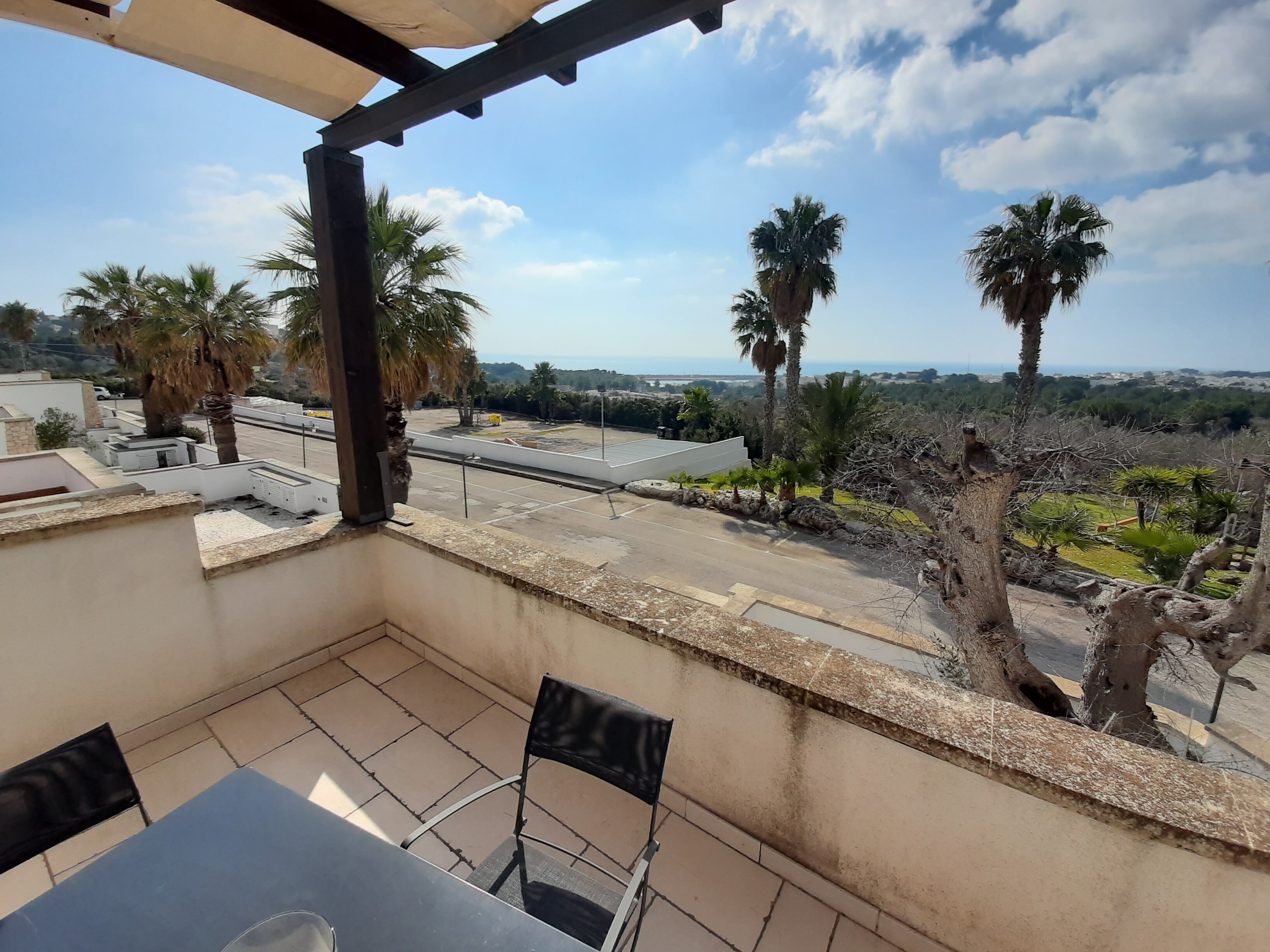 A balcony with a view of palm trees and a road.