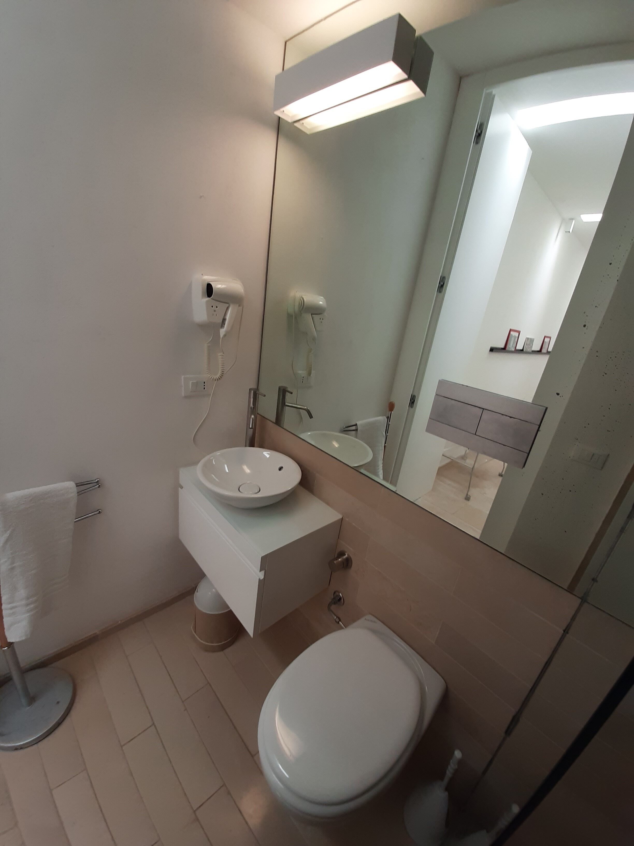 A modern bathroom with a white sink, a toilet, and a mirror.