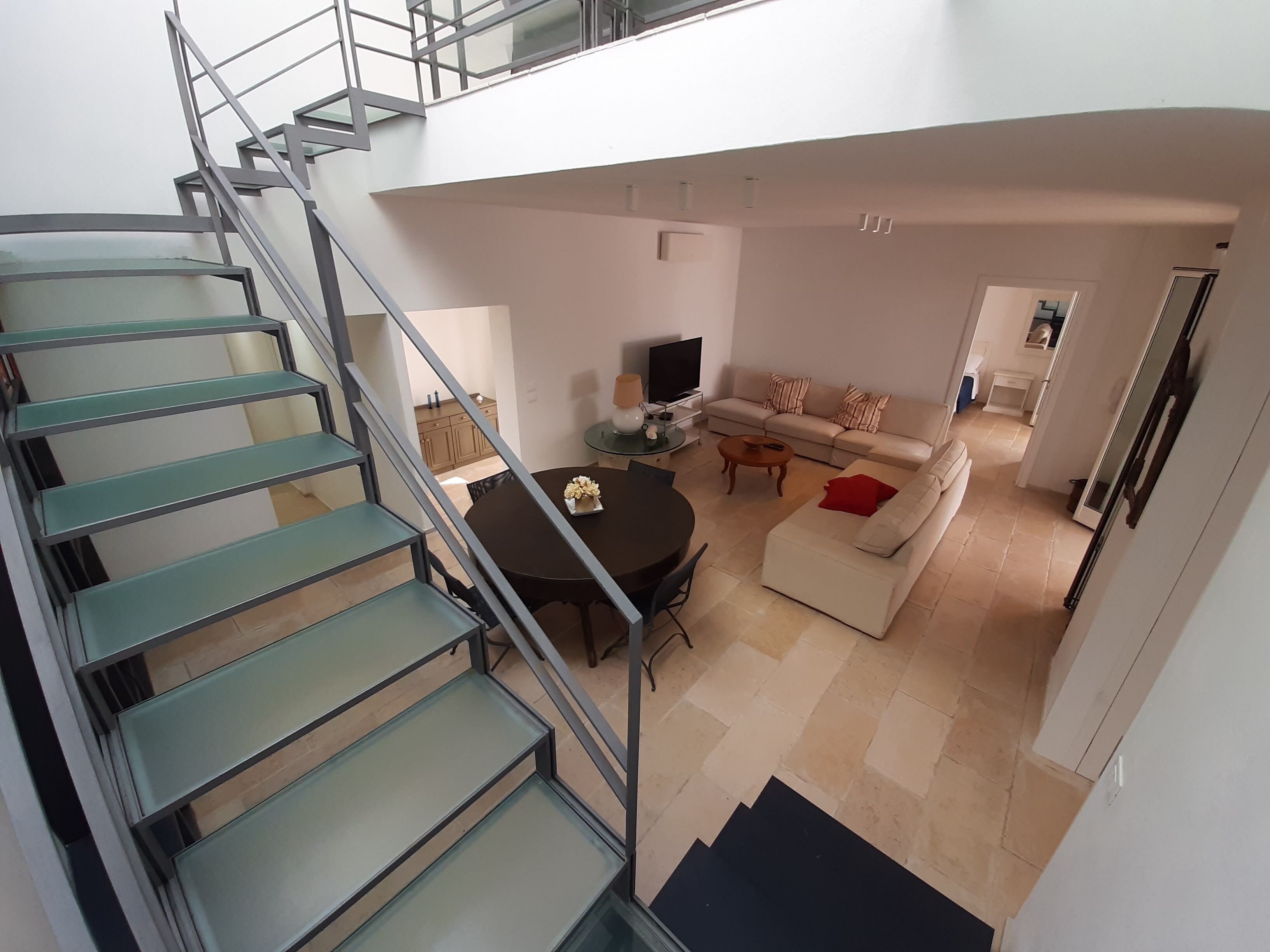 Ein modernes Wohnzimmer mit Treppe, Sofa, Couchtisch und Fernseher.