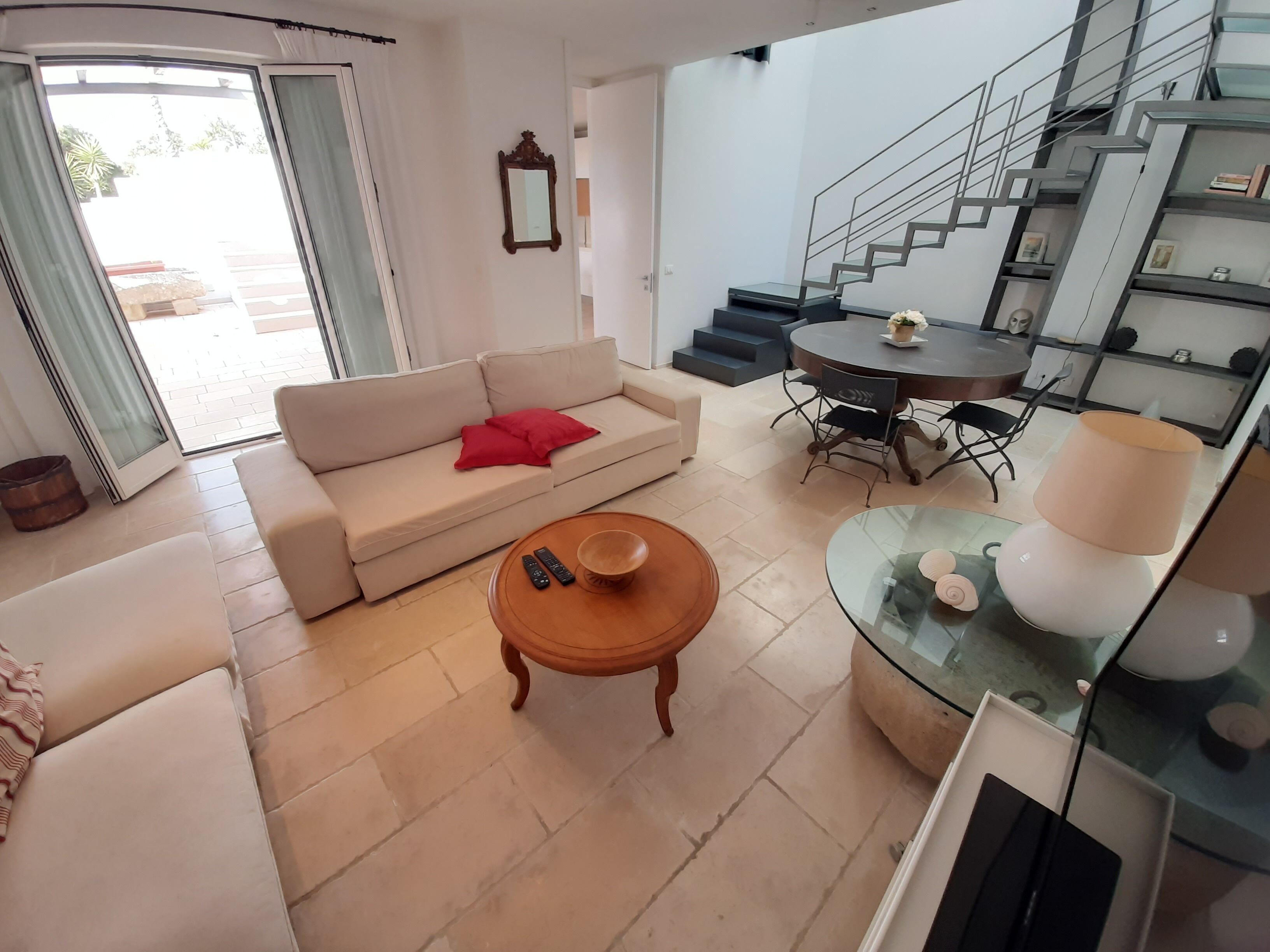 Un salon moderne comprenant un canapé, une table basse et un coin repas avec une table et des chaises en verre.