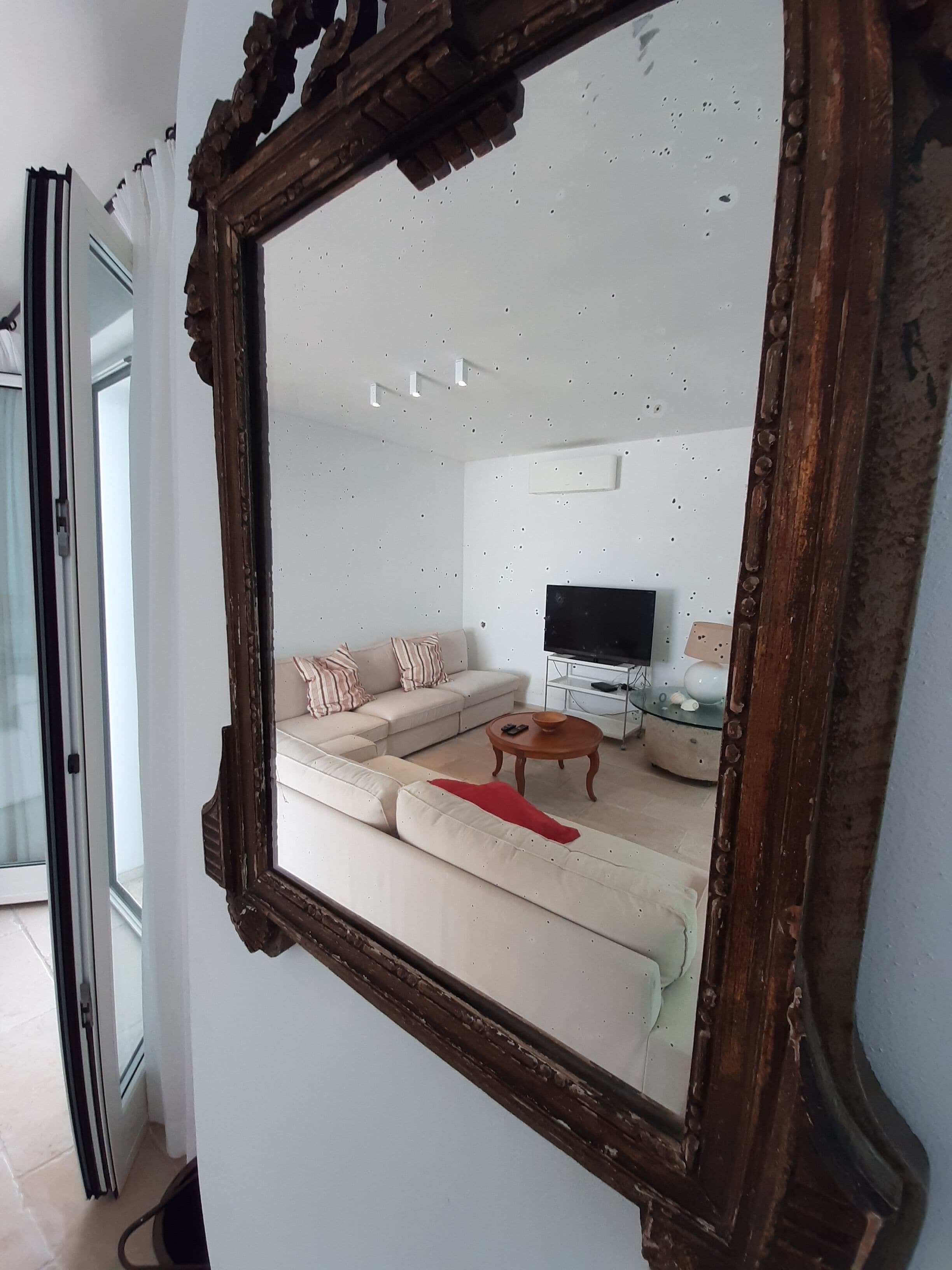 A living room with a large mirror, a sofa, a coffee table, and a television.