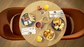 A round dining table with breakfast items including toast, croissants, and fruit.