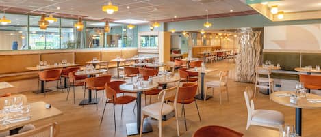 Un restaurante espacioso con varias zonas de comedor, incluyendo cabinas y mesas.