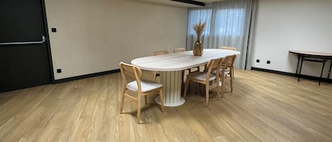 A conference room with a round table, six chairs, and a vase of dried plants.