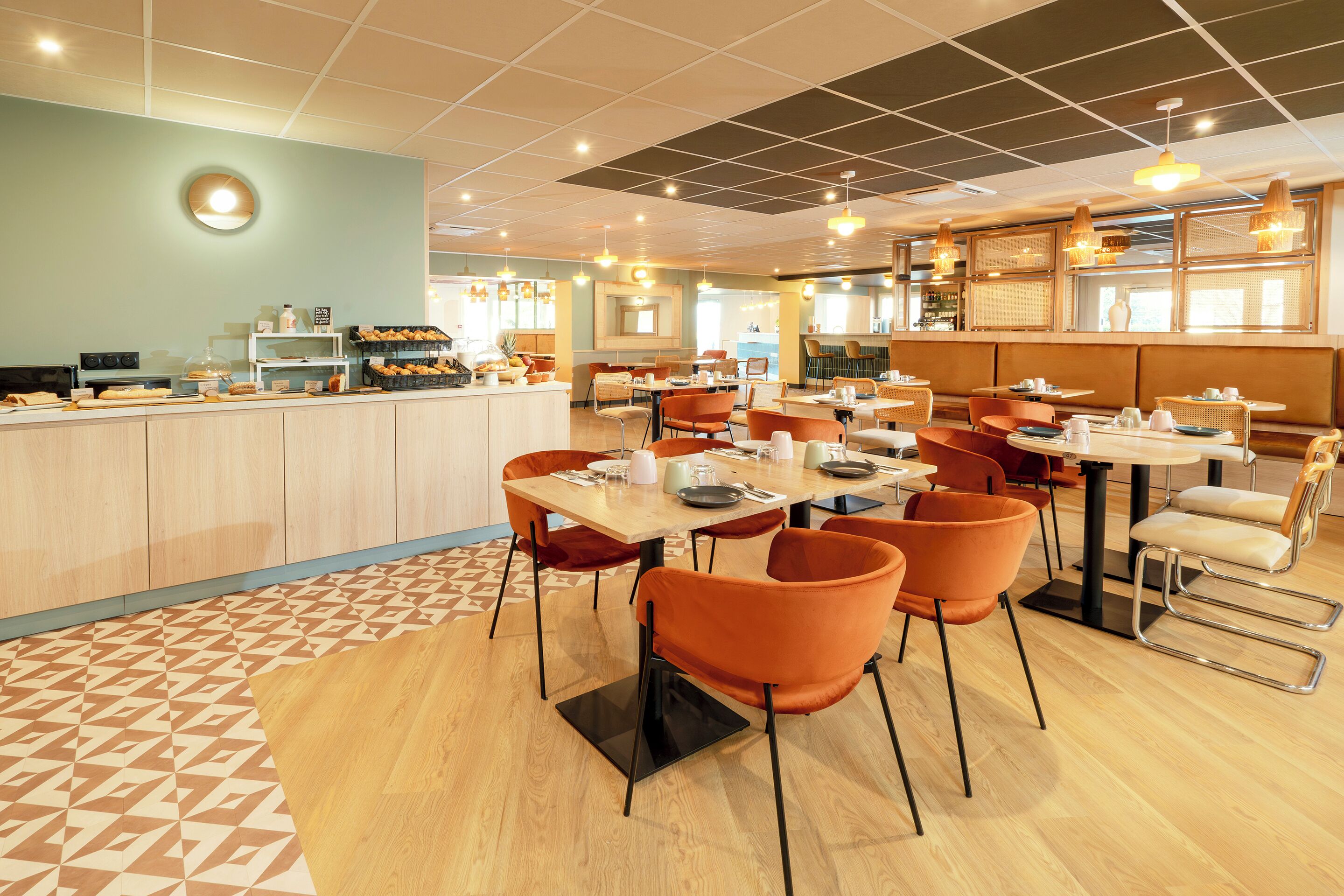 En modern restaurang med en central bardisk, flera bord och orange stolar.