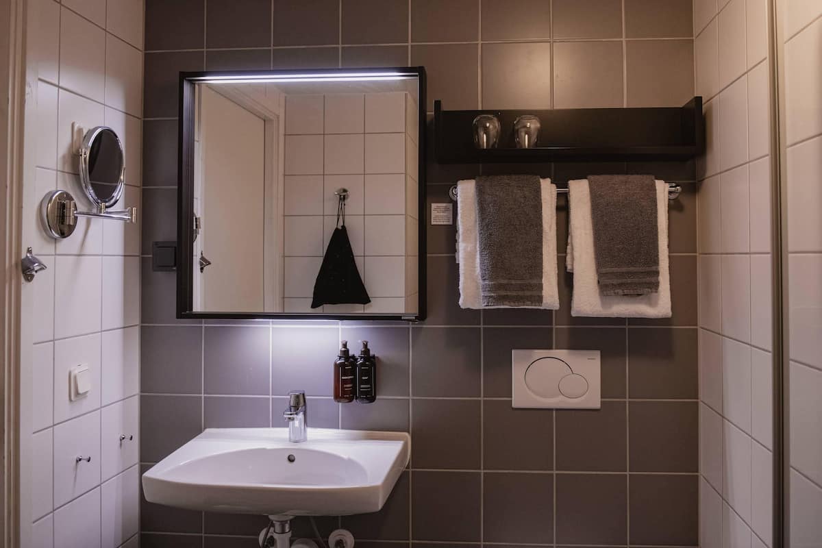 A bathroom with a sink, mirror, towel rack, and a wall-mounted heater.