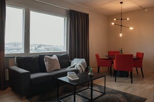 Una sala de estar moderna con sofá, mesa de centro y comedor con sillas rojas.