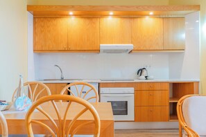 A compact kitchen with wooden cabinets, a white countertop, and a built-in oven.