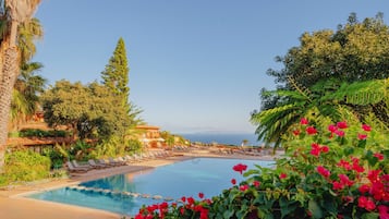 Una piscina con sillones de descanso y vista al océano.