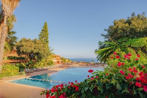 A pool with lounge chairs and a view of the ocean.
