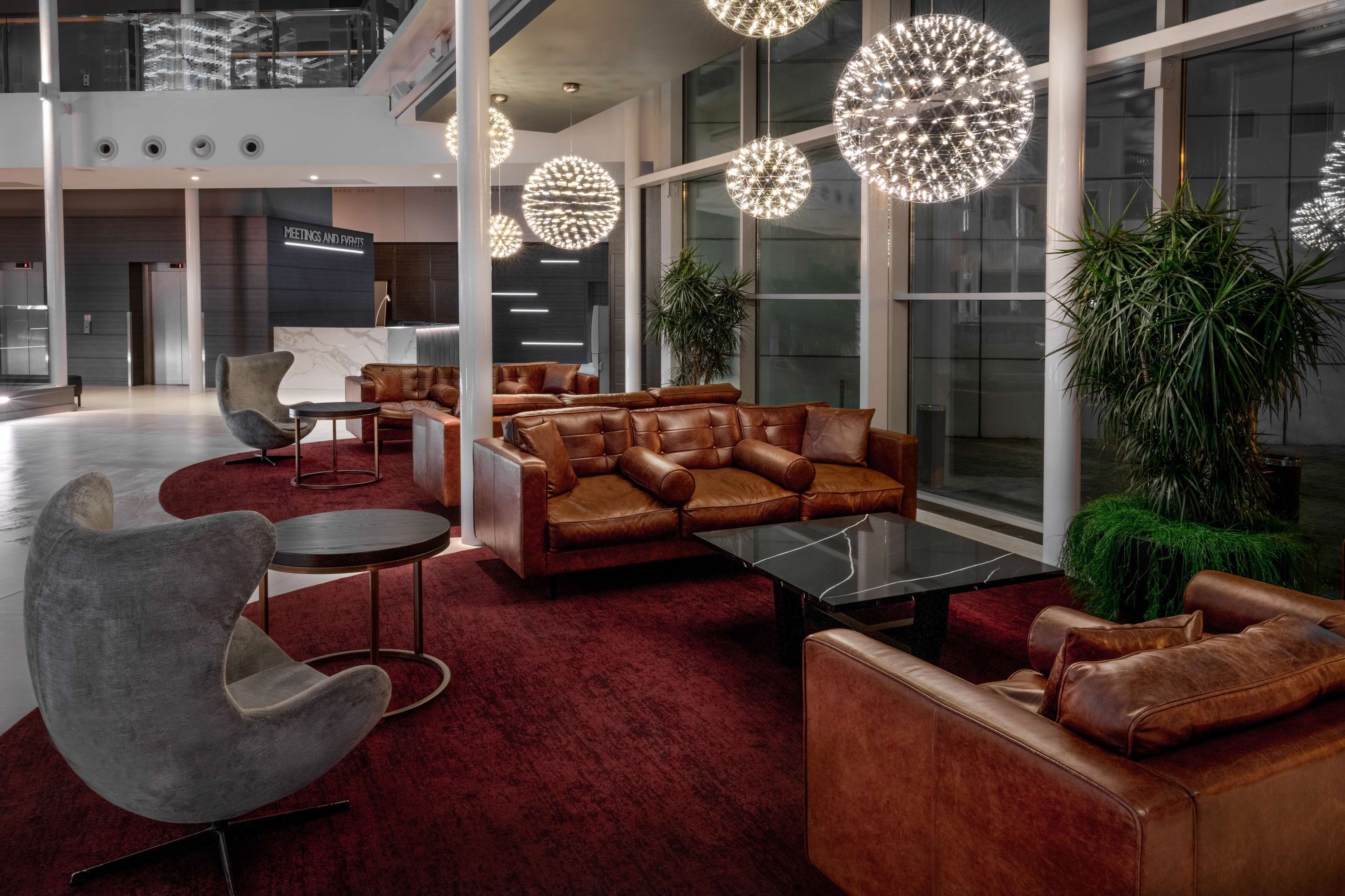 A modern lobby with leather sofas, a marble coffee table, and unique spherical lighting fixtures.
