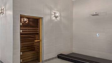 A modern bathroom with a wooden door, tiled walls, a shower area, and a small step leading to a showerhead.