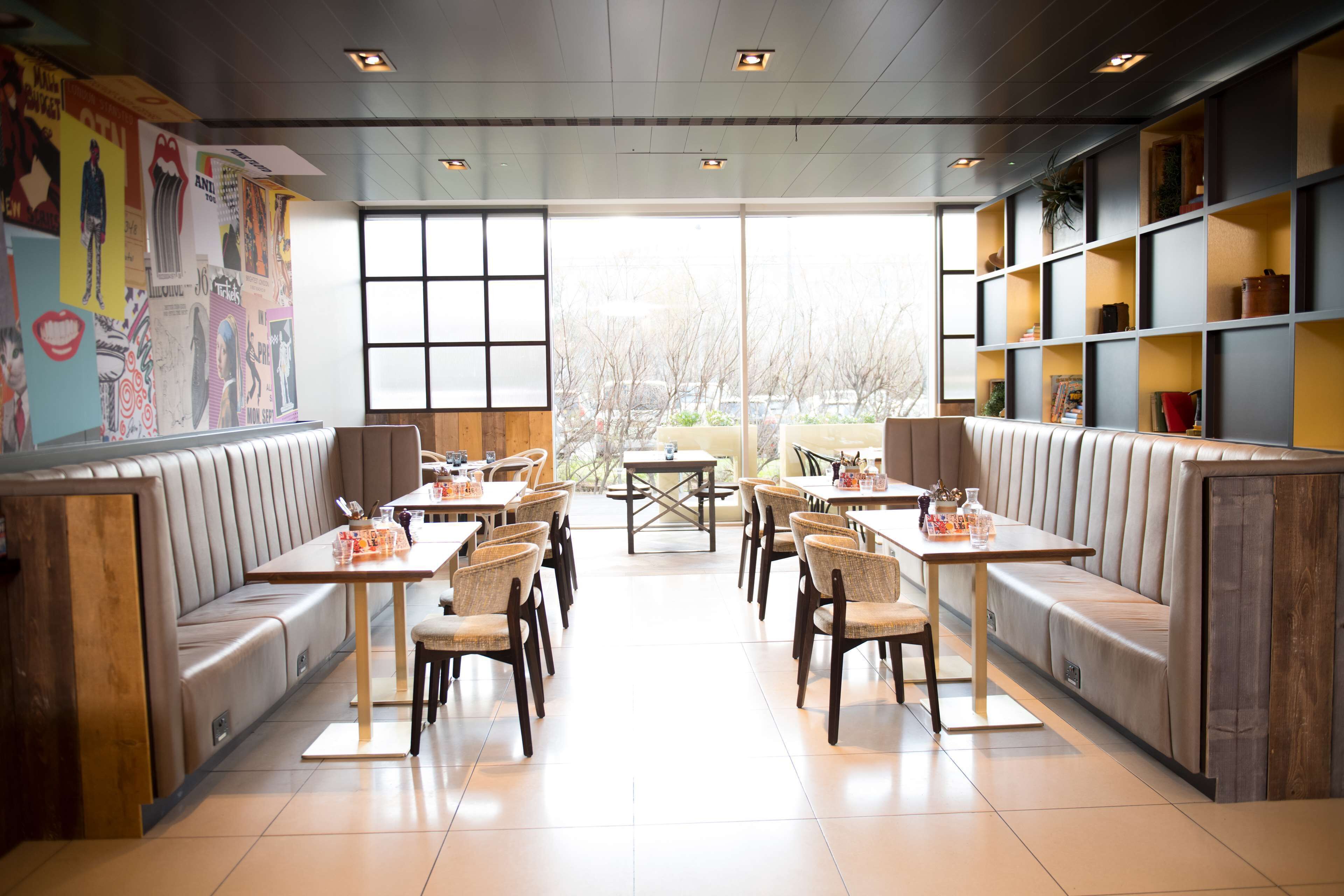 A restaurant with booth seating and tables, large windows, and a view of the outside.