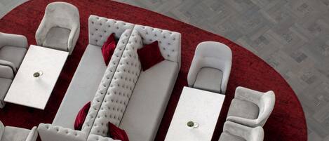 Una habitación de hotel moderna con alfombra roja, sofás blancos y sillones a juego.