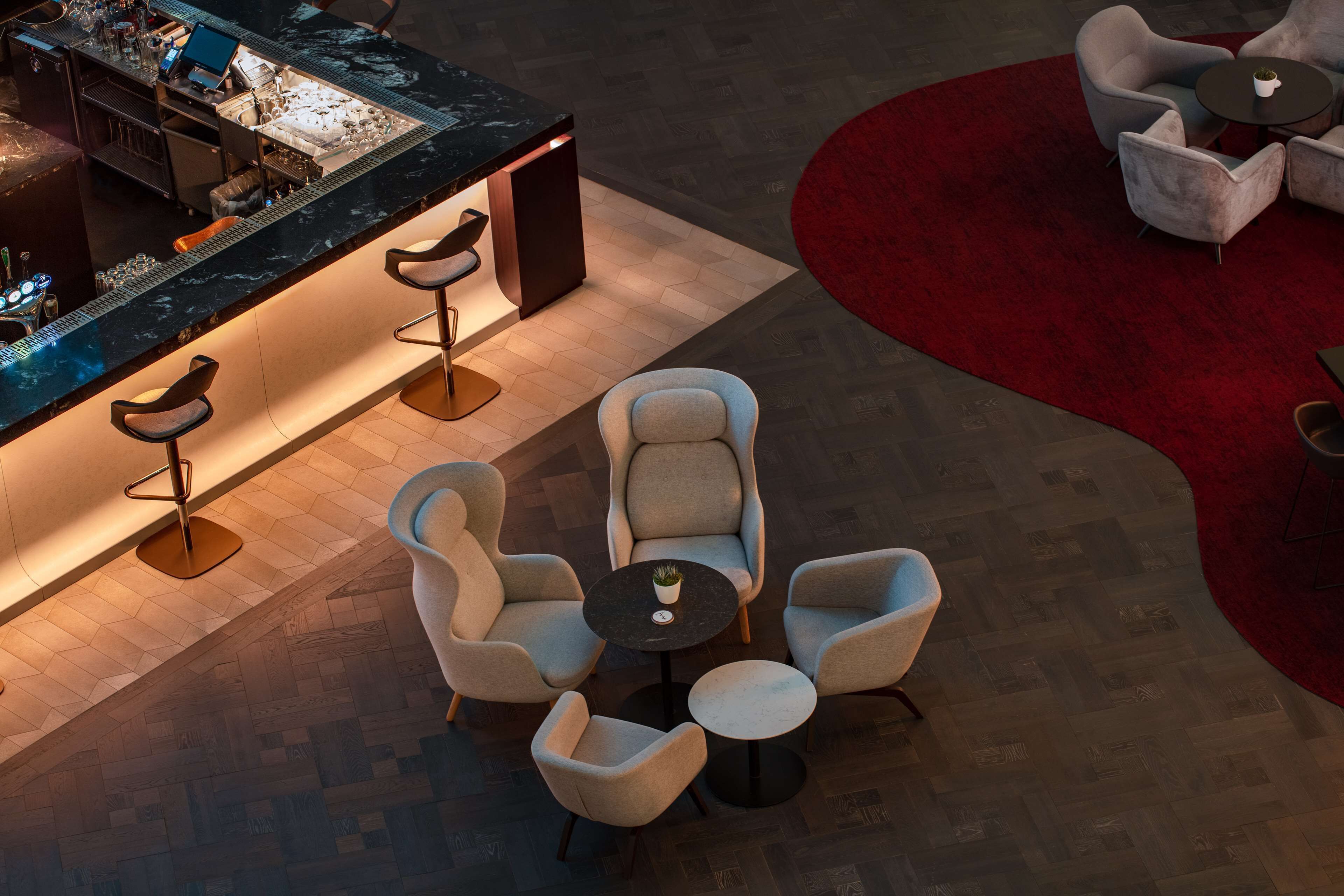 A bar area with a counter, stools, and a seating area with round tables and chairs.