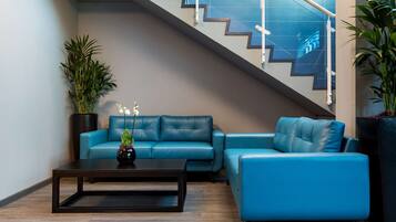 Ein modernes Wohnzimmer mit einem blauen Sofa, einem Couchtisch und einer Treppe mit Glasgeländern.