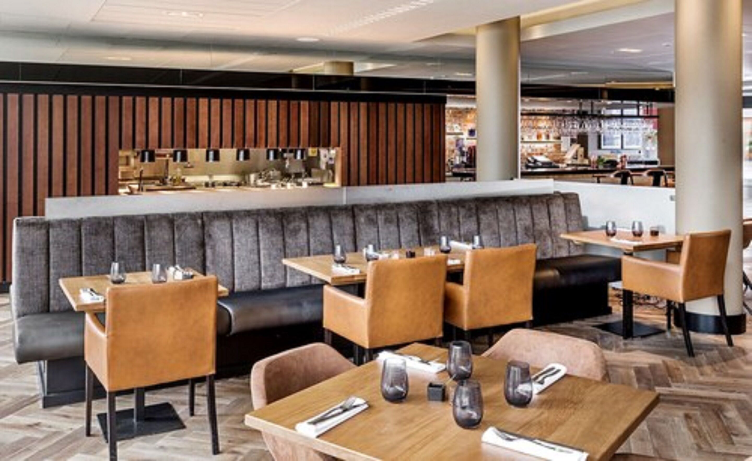 Un restaurant avec des banquettes et des tables, un plancher en bois et un bar situé au fond de la salle.