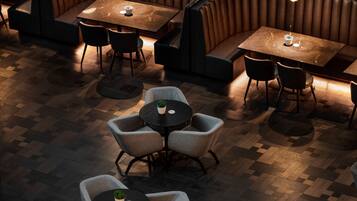 A restaurant with booth seating and round tables, featuring a herringbone floor pattern and pendant lighting.