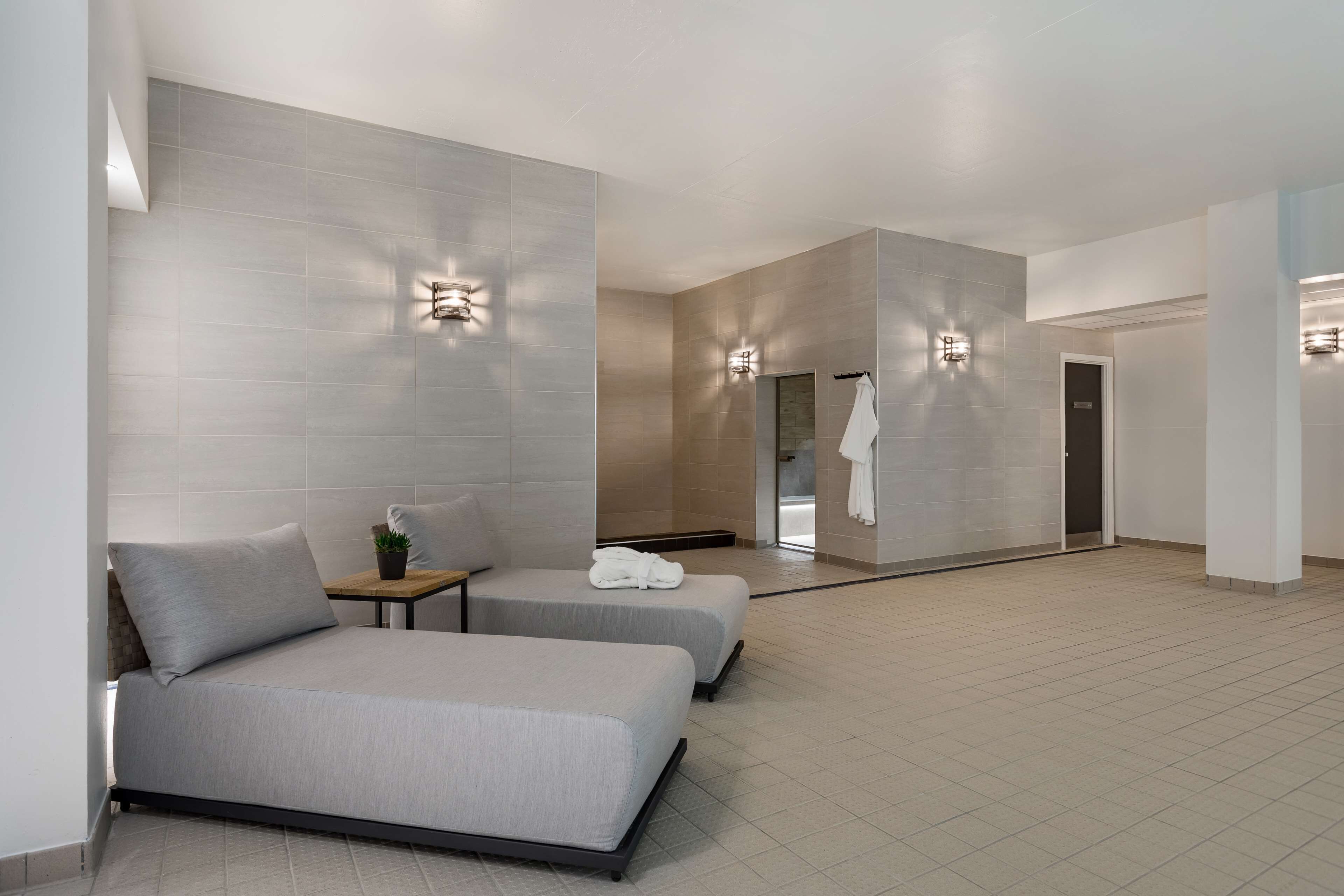 A modern hotel room with two beds, a small table with a plant, and wall-mounted lights.
