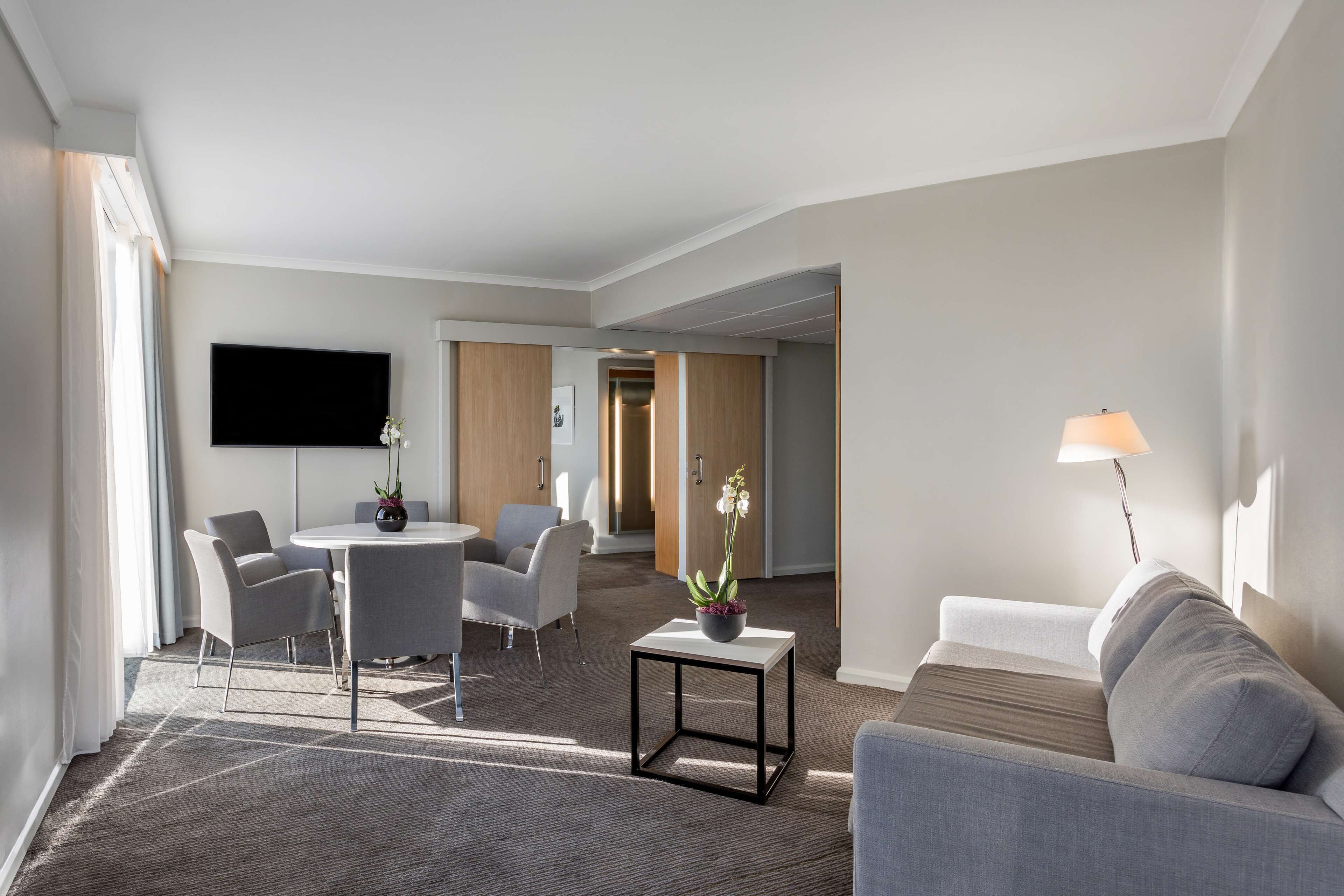 Een moderne hotelkamer met een eethoek, een bank en een televisie.