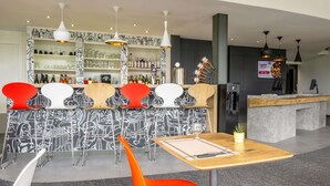 A modern bar area with a counter, bar stools, and a variety of bottles.