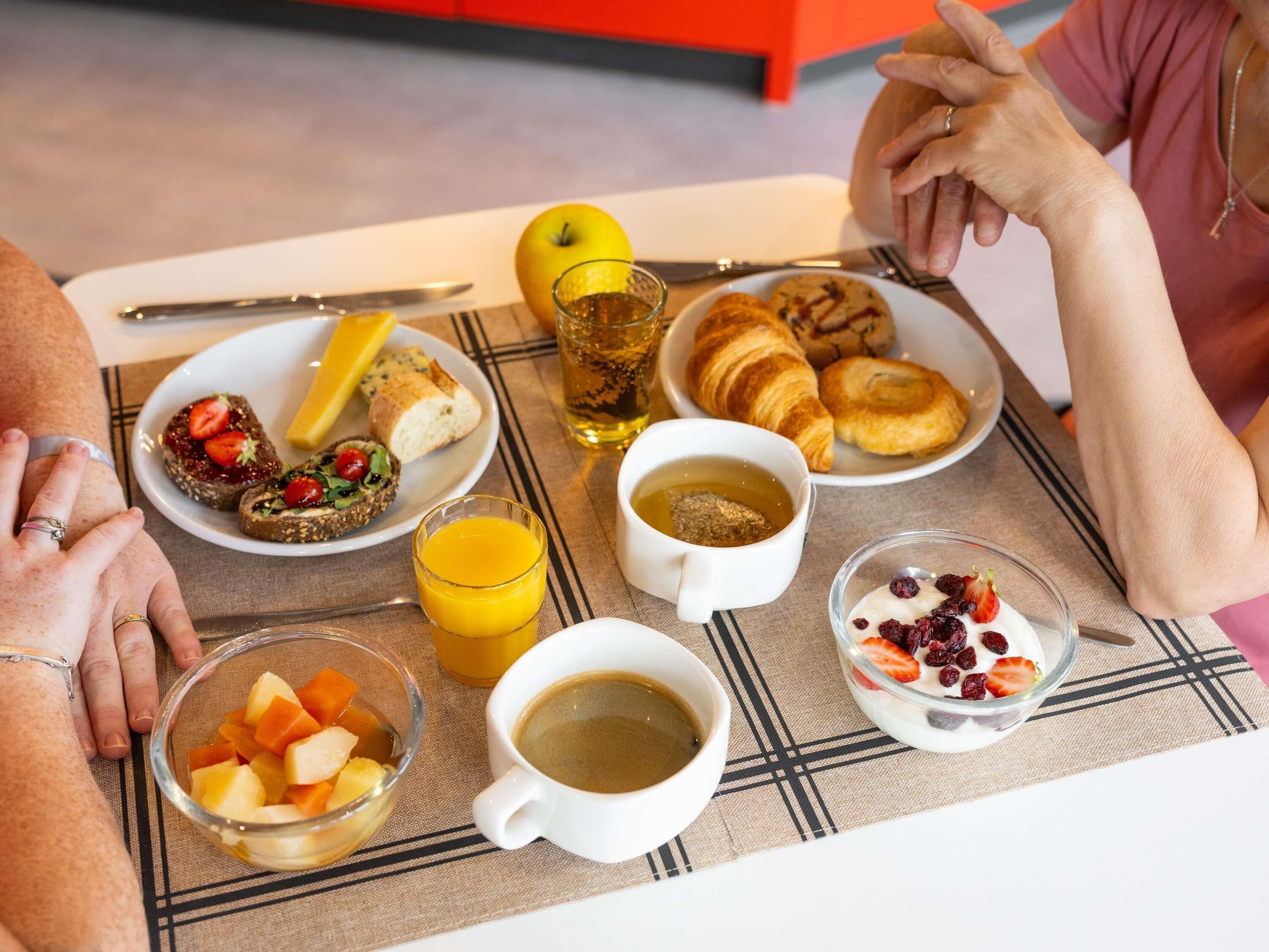 A breakfast setting with various food items and drinks on a table.