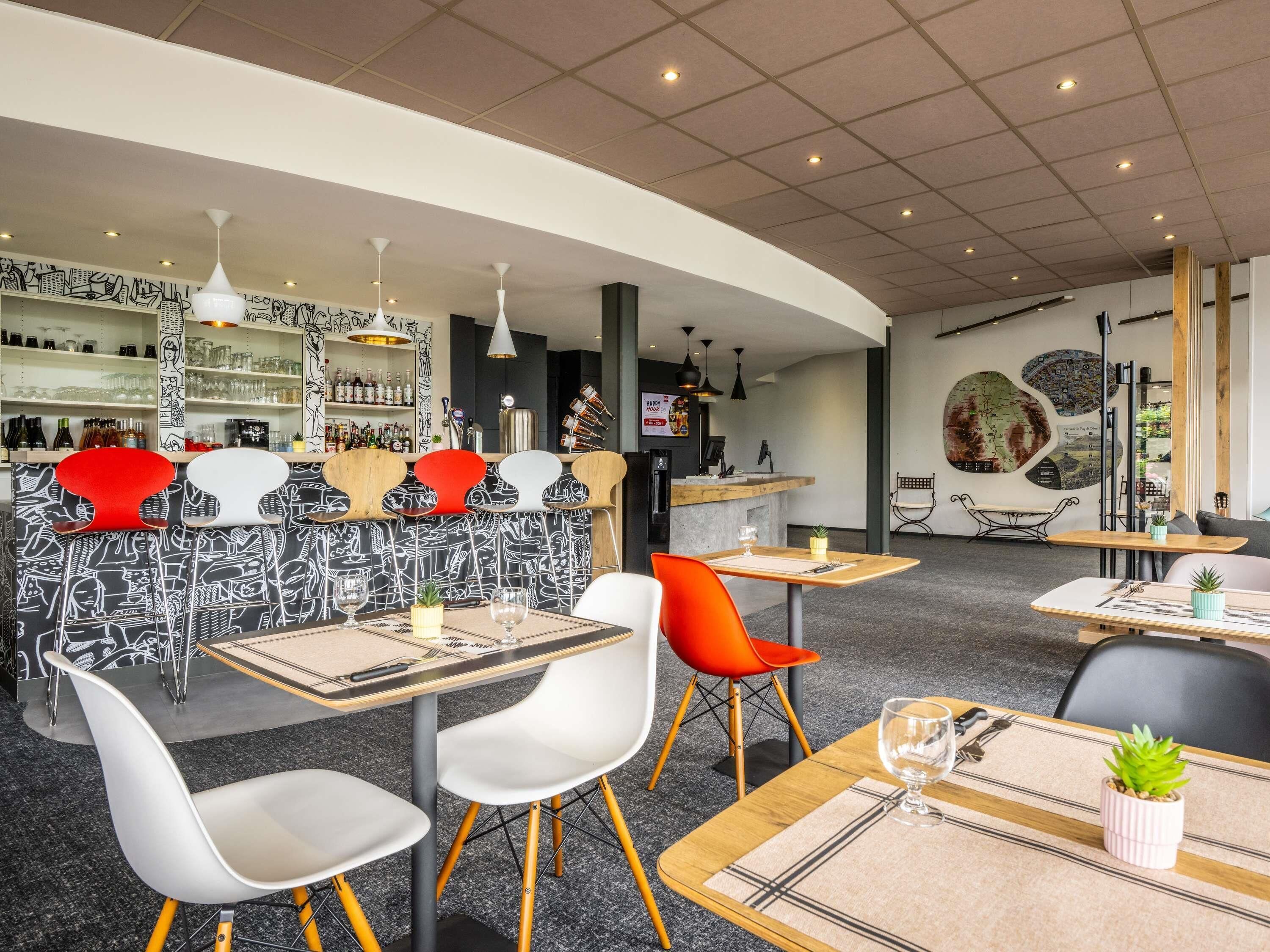 Un intérieur de restaurant moderne avec un bar, des tables et des chaises, et une carte affichée au mur.