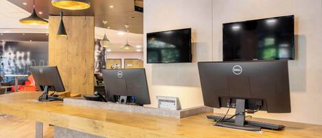 A reception desk with multiple monitors, wooden counter, and pendant lighting.